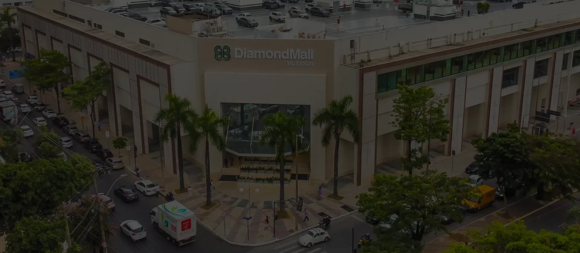 Fachada iluminada do shopping DiamondMall com o céu anoitecendo ao fundo e prédios