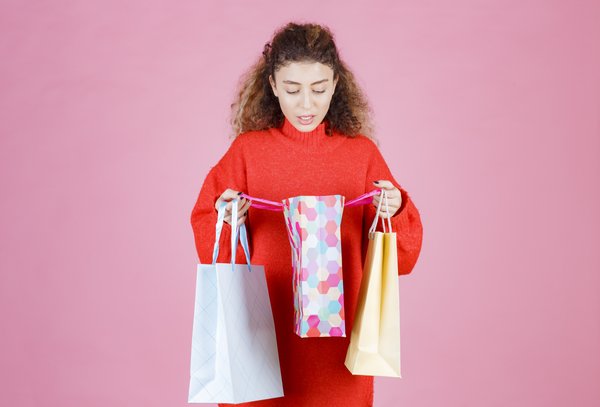 mulher-abrindo-suas-sacolas-de-compras-coloridas-e-verificando-os-produtos